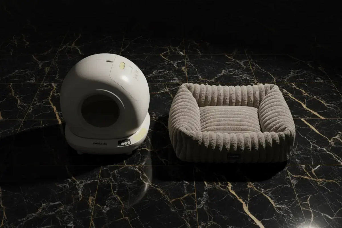 White globe litter tray and empty ribbed bolster bed on black marble