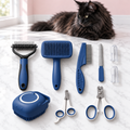 Cashmere Comb nine-piece blue grooming set with a black Maine Coon in an empty light pink room on white marble.