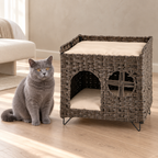 The Foldaway Wicker House beside a solid-blue British Shorthair in a sparse luxury bedroom