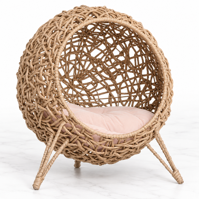 Large cat rattan pod bed with pink cushion on a light marble background