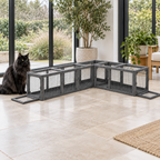 Full-sized black Norwegian Forest cat beside the modular wooden cat tunnel in a garden room