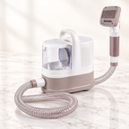 White and taupe 1.3 litre grooming vacuum with one hose and grooming head on light marble
